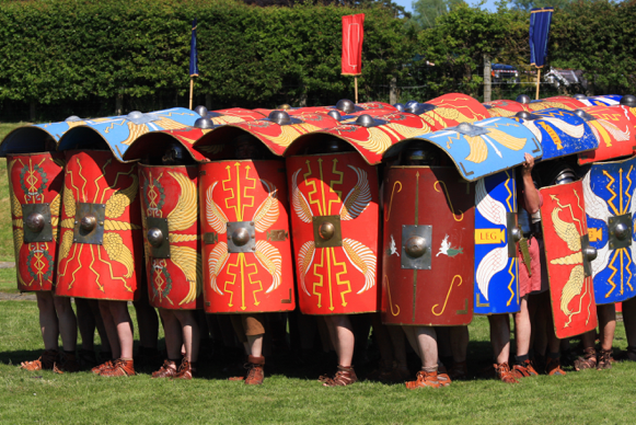 Group of people covering themselves in decorated shields. Medieval styled 